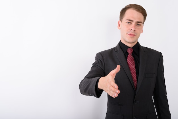 Young handsome businessman wearing suit on white wall