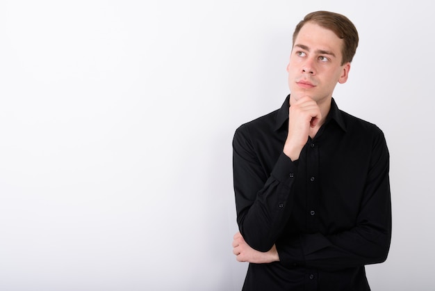 Young handsome businessman on white wall