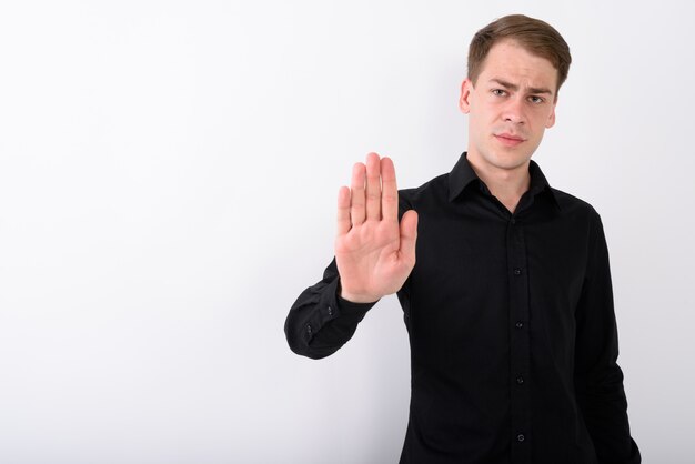 Young handsome businessman on white wall