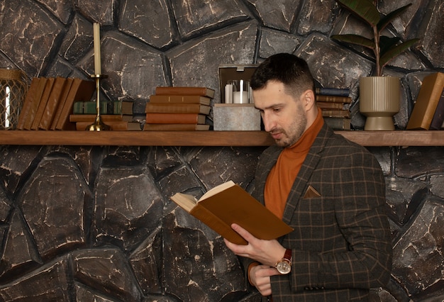 Young handsome businessman with beard in suit reading book