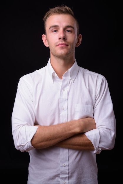  young handsome businessman with blond hair against black wall