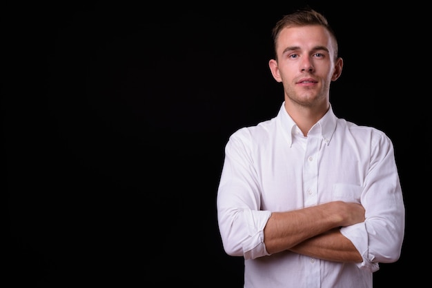  young handsome businessman with blond hair against black wall