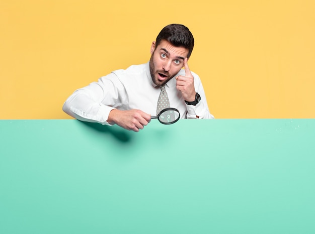 Photo young handsome businessman with a magnifying glass. search concept