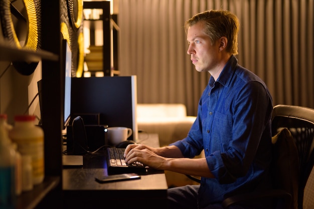 Young handsome businessman working overtime at home late at night