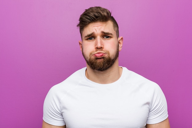 Photo young handsome caucasian man blows cheeks, has tired expression. facial expression concept.