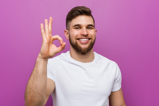 Young handsome caucasian man cheerful and confident showing ok gesture.