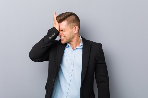 Young handsome caucasian man forgetting something, slapping forehead with palm and closing eyes.