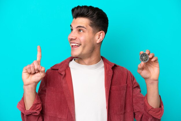 Young handsome caucasian man holding compass intending to realizes the solution while lifting a finger up