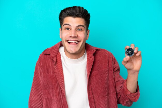 Young handsome caucasian man holding compass with surprise and shocked facial expression