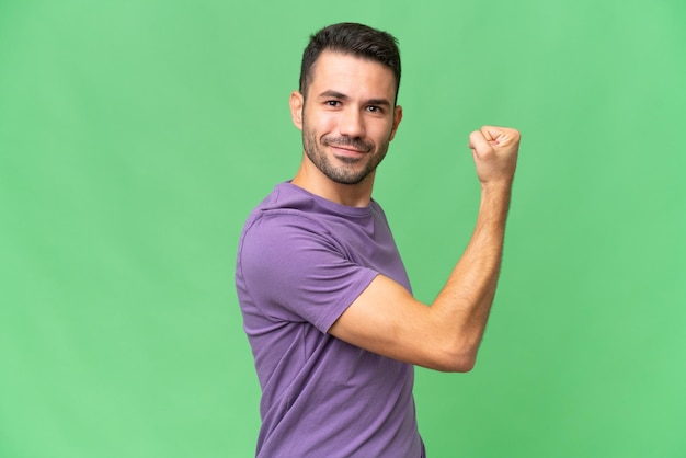 young handsome caucasian man over isolated background doing strong gesture
