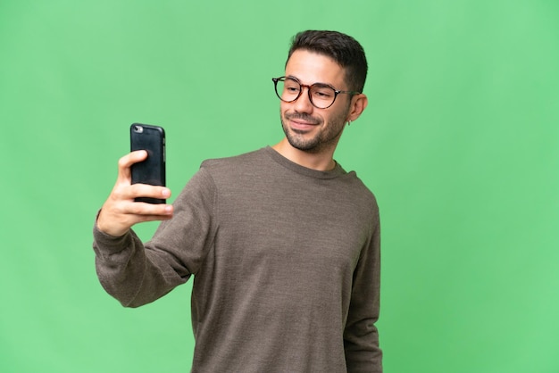 Selfie を作る孤立した背景に若いハンサムな白人男性