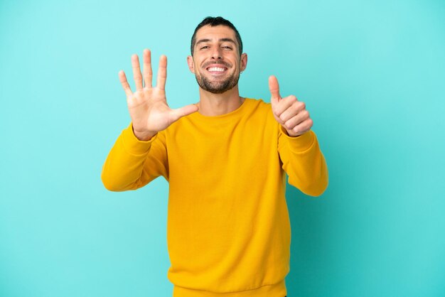 Young handsome caucasian man isolated on blue background counting six with fingers