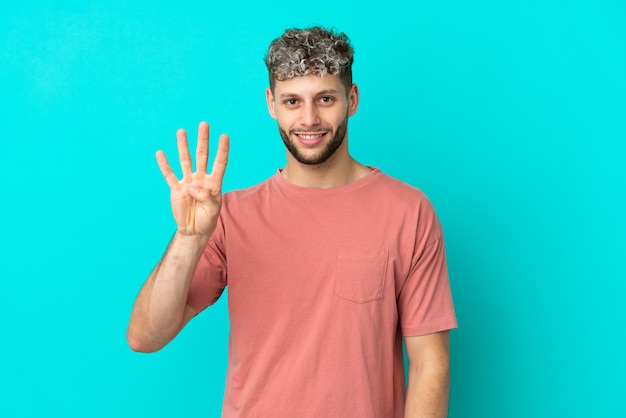 Young handsome caucasian man isolated on blue background happy and counting four with fingers