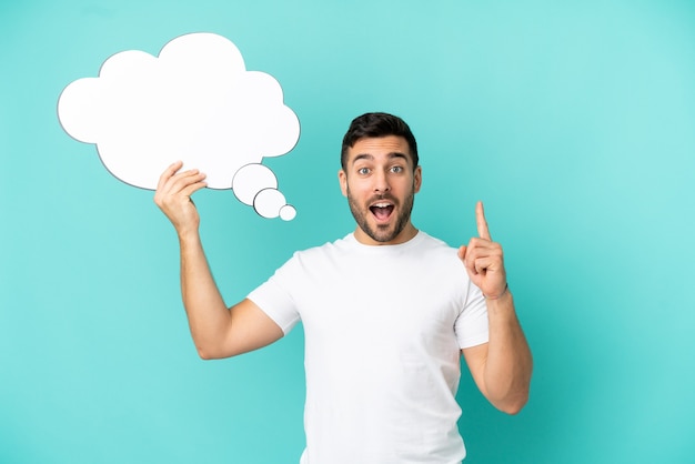 Young handsome caucasian man isolated on blue background holding a thinking speech bubble