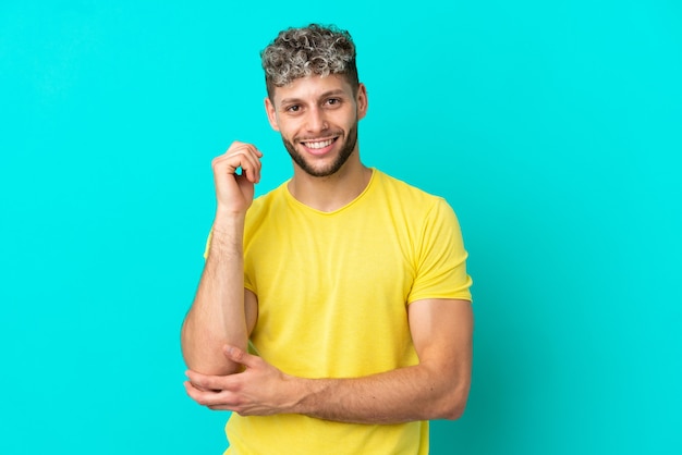 Young handsome caucasian man isolated on blue background laughing