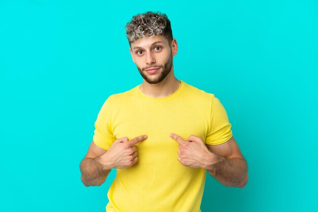 Young handsome caucasian man isolated on blue background pointing to oneself