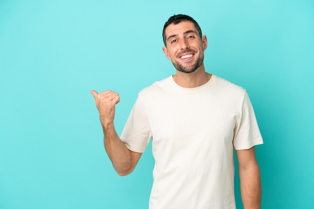 Young handsome caucasian man isolated on blue background pointing to the side to present a product