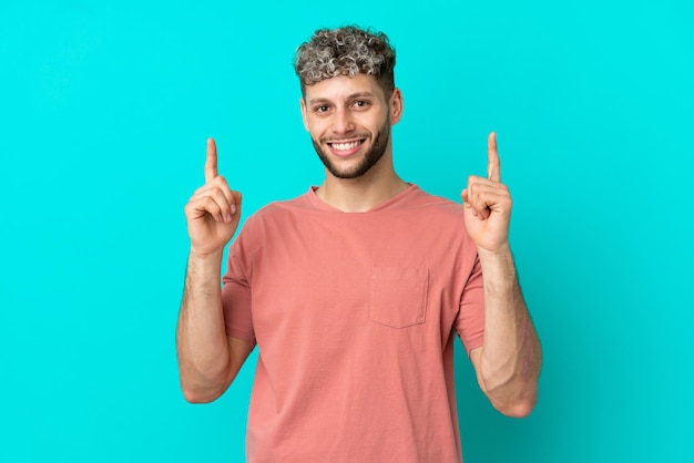 Young handsome caucasian man isolated on blue background pointing up a great idea