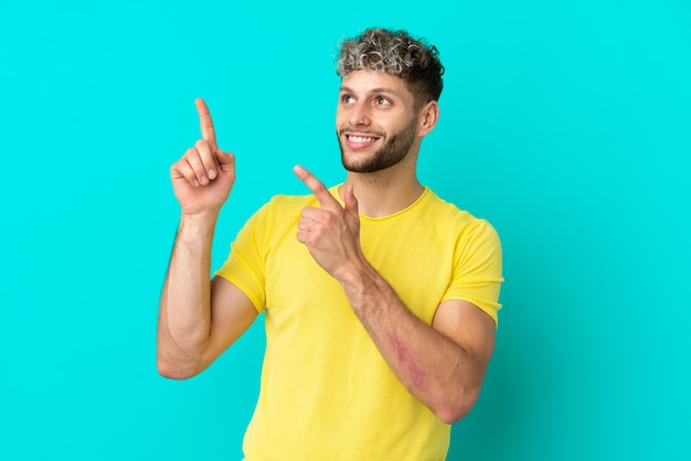 Young handsome caucasian man isolated on blue background pointing with the index finger a great idea