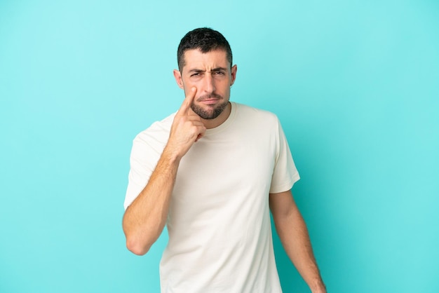 Young handsome caucasian man isolated on blue background showing something