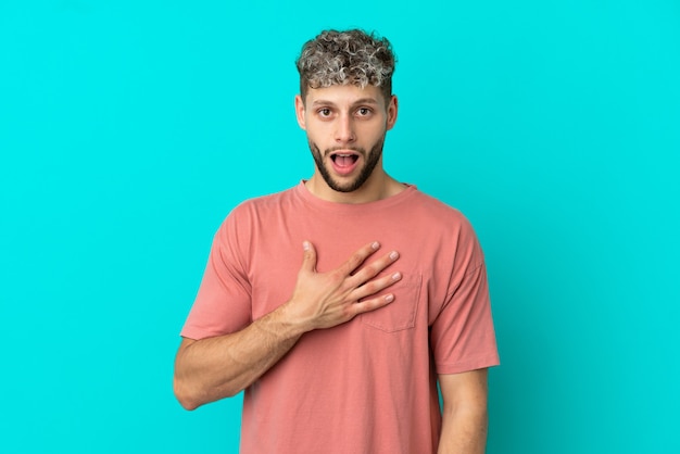 Young handsome caucasian man isolated on blue background surprised and shocked while looking right