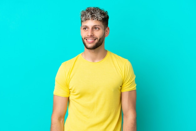 Young handsome caucasian man isolated on blue background thinking an idea while looking up