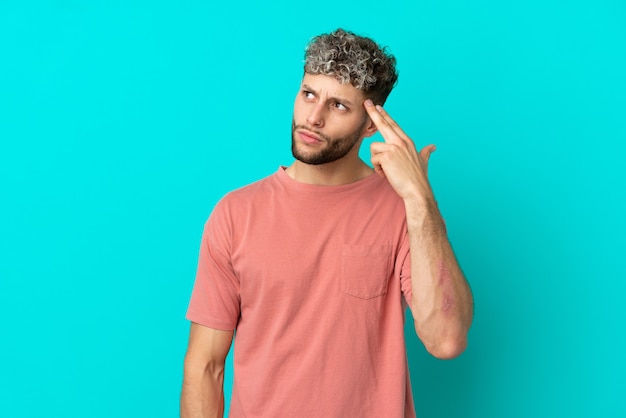 Young handsome caucasian man isolated on blue background with problems making suicide gesture