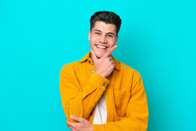 Young handsome caucasian man isolated on blue bakcground happy and smiling