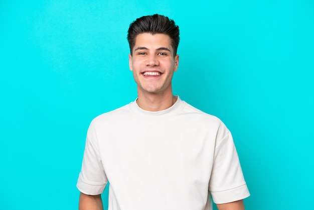 Young handsome caucasian man isolated on blue bakcground laughing