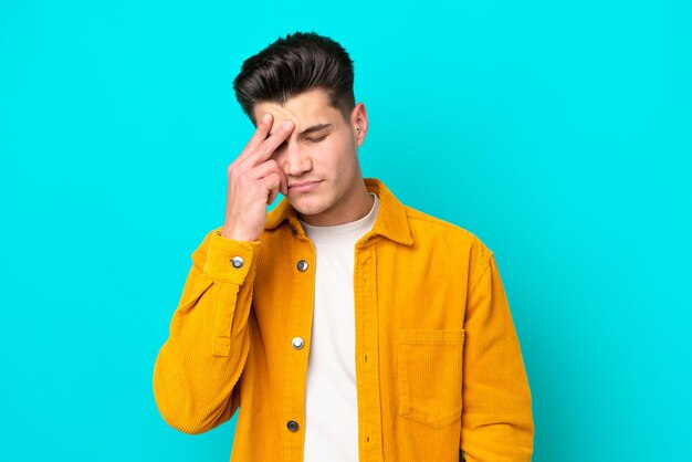 young handsome caucasian man isolated on blue bakcground with headache