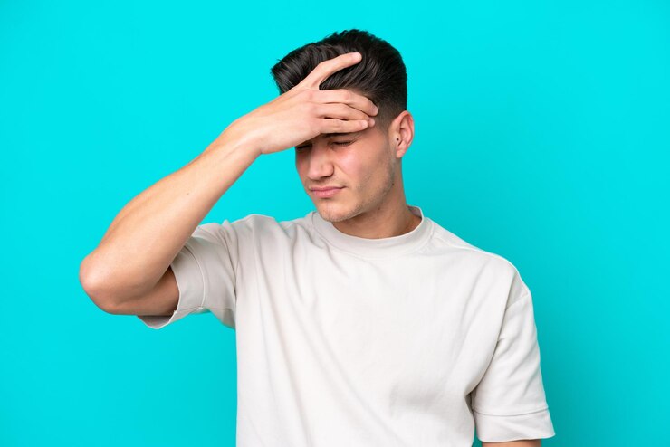 Photo young handsome caucasian man isolated on blue bakcground with headache