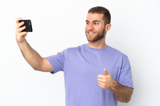 Young handsome caucasian man isolated making a selfie with mobile phone