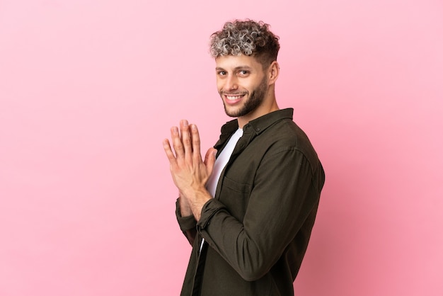 Young handsome caucasian man isolated on pink background scheming something