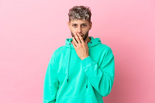 Young handsome caucasian man isolated on pink background surprised and shocked while looking right