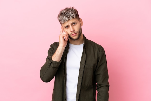 Young handsome caucasian man isolated on pink background thinking an idea