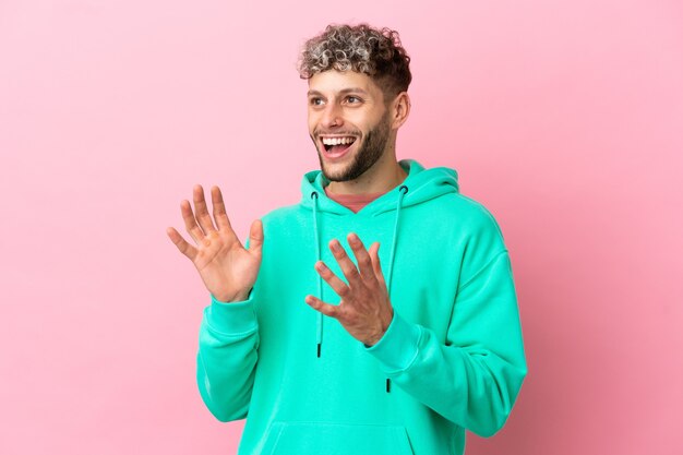 Young handsome caucasian man isolated on pink background with surprise facial expression