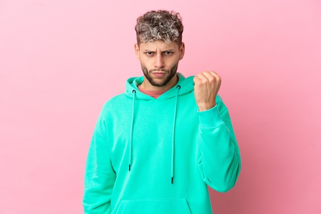 Young handsome caucasian man isolated on pink background with unhappy expression