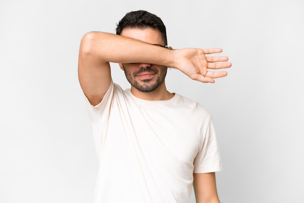 Young handsome caucasian man over isolated white background covering eyes by hands