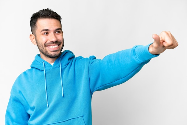 Young handsome caucasian man over isolated white background giving a thumbs up gesture