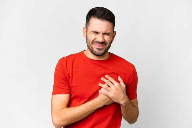 Young handsome caucasian man over isolated white background having a pain in the heart