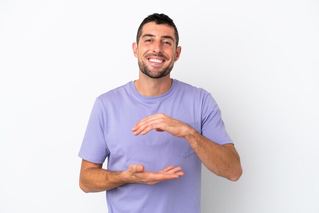 Young handsome caucasian man isolated on white background holding copyspace imaginary on the palm to insert an ad