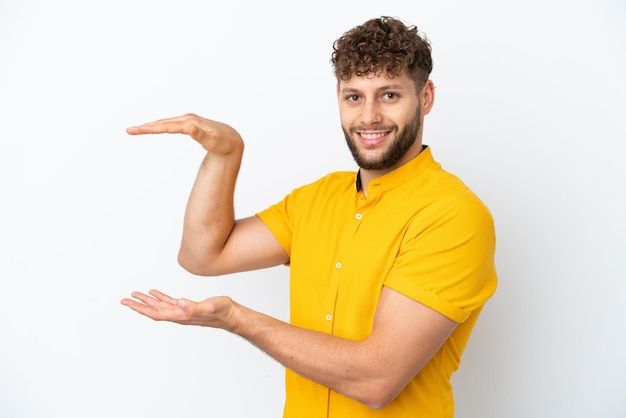 Young handsome caucasian man isolated on white background holding copyspace to insert an ad