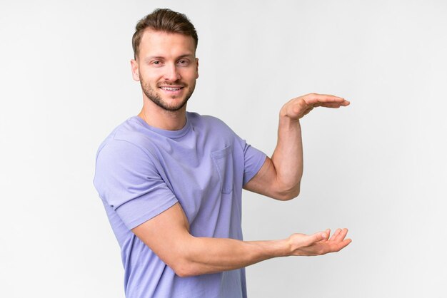 Young handsome caucasian man over isolated white background holding copyspace to insert an ad