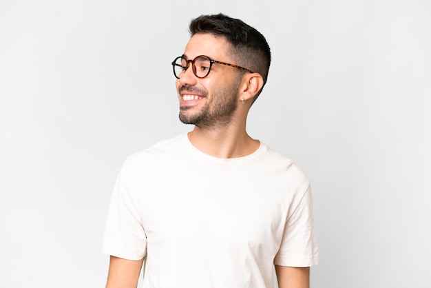 Young handsome caucasian man over isolated white background looking to the side and smiling