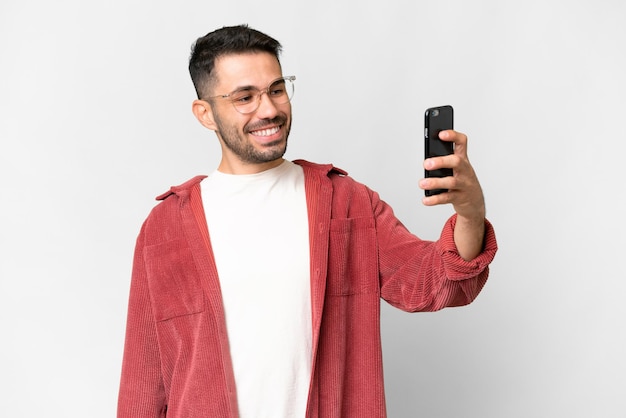 Young handsome caucasian man over isolated white background making a selfie