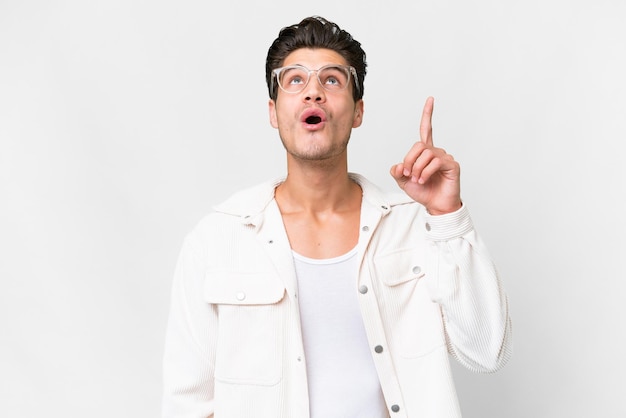 Young handsome caucasian man over isolated white background pointing up and surprised