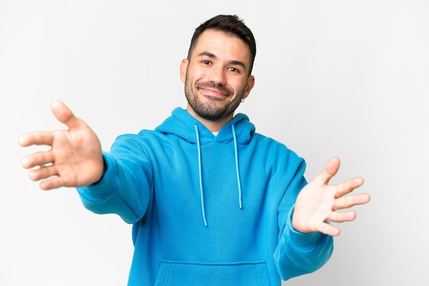 Young handsome caucasian man over isolated white background presenting and inviting to come with hand