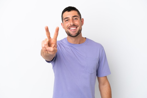 Young handsome caucasian man isolated on white background smiling and showing victory sign