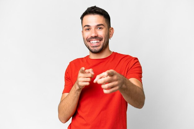 Young handsome caucasian man over isolated white background surprised and pointing front