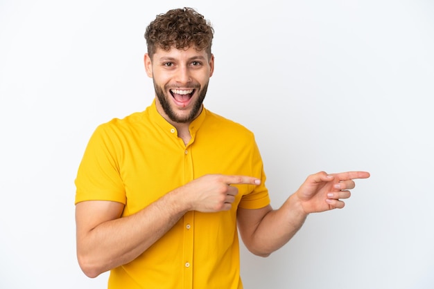 Young handsome caucasian man isolated on white background surprised and pointing side